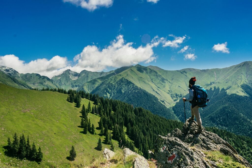 a person standing on a rock with a backpack and poles on a mountain